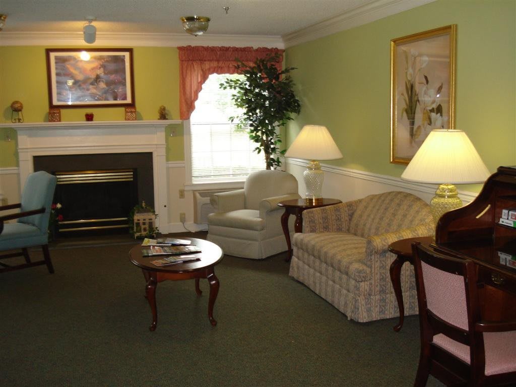 A cozy living room with a sofa, armchairs, and a fireplace.