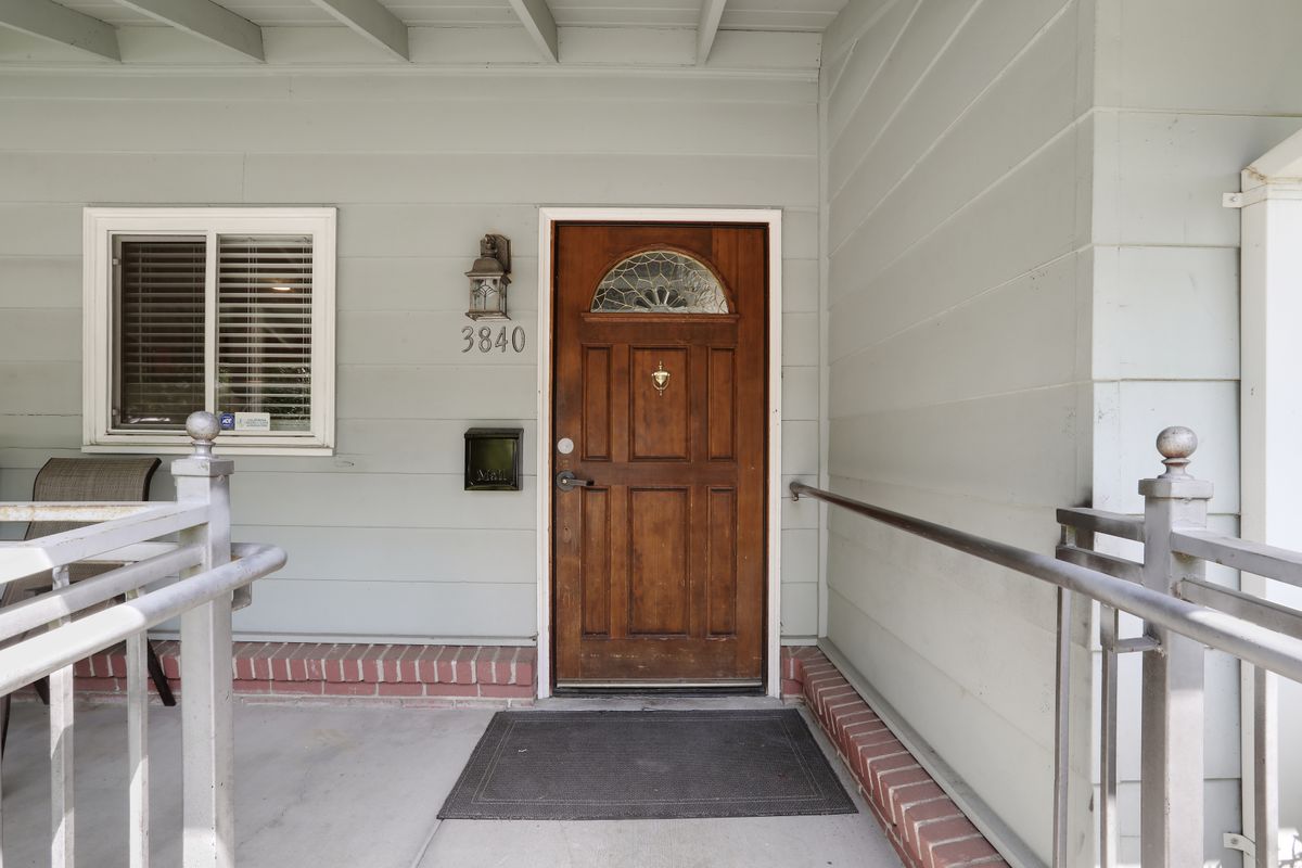 Front entrance of a house with a wooden door and a welcome mat.