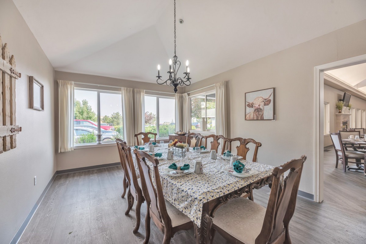 A well-decorated dining room with a long wooden table and elegant chandelier.
