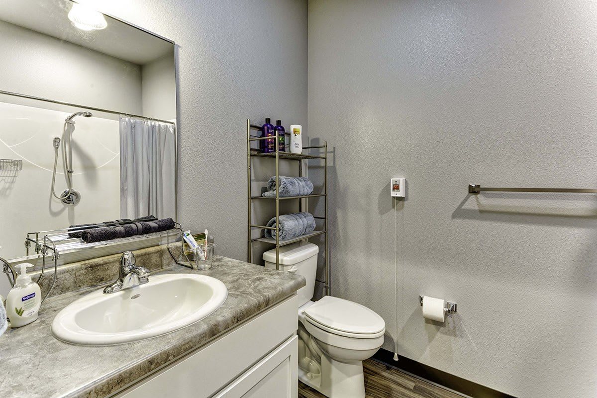 A modern bathroom with a sink, toilet, and towel storage.