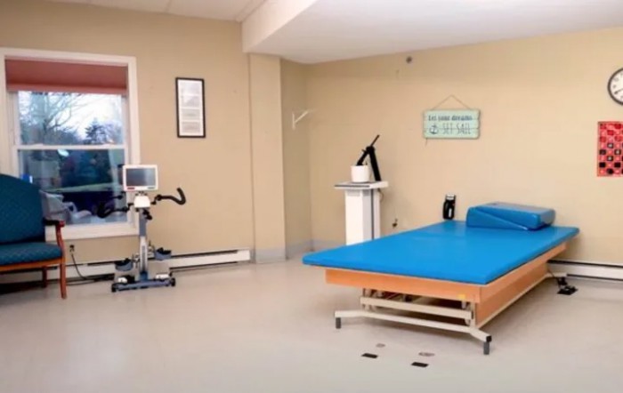 A rehabilitation room equipped with exercise equipment and a treatment bed for physical therapy.