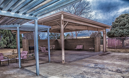 An empty outdoor patio area with a canopy and benches, set against a cloudy sky.