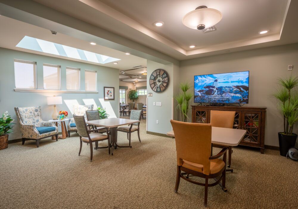 A cozy living room with comfortable seating, a large television, and skylights for natural lighting.