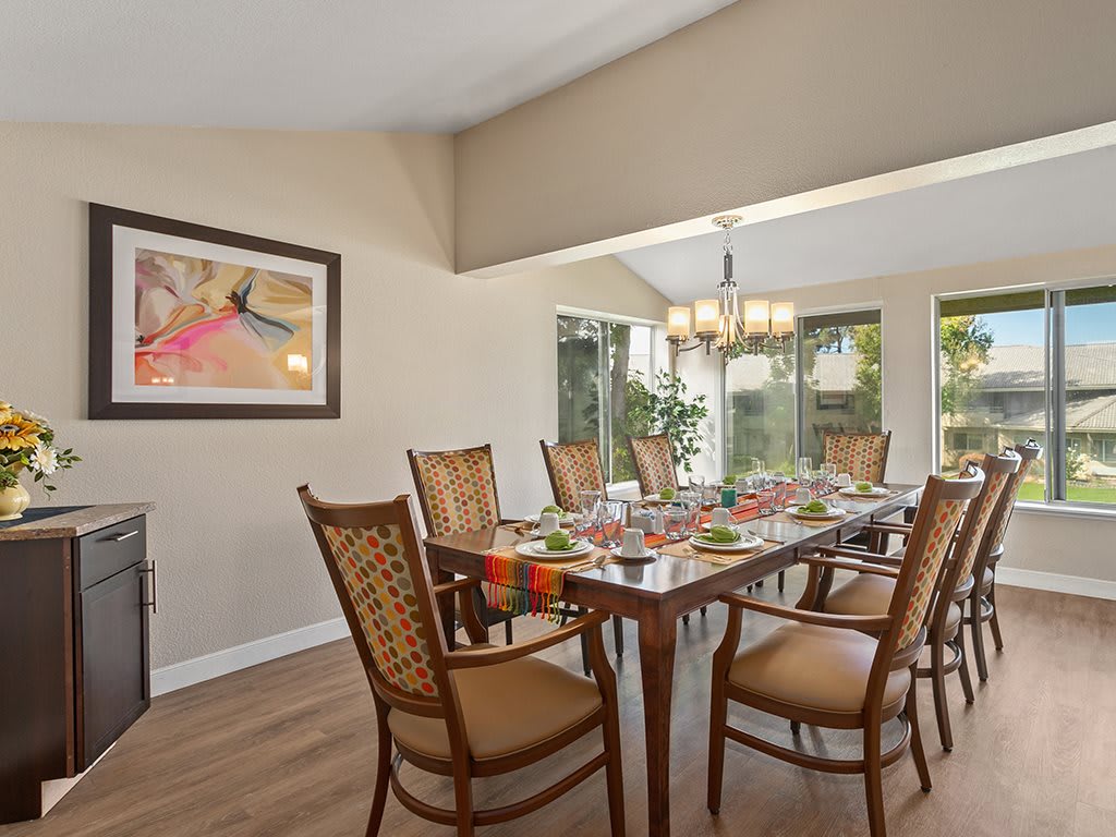 A well-decorated dining room with a set table and elegant chandelier.