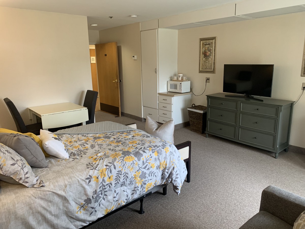 A cozy apartment bedroom with a bed, dresser, and television.