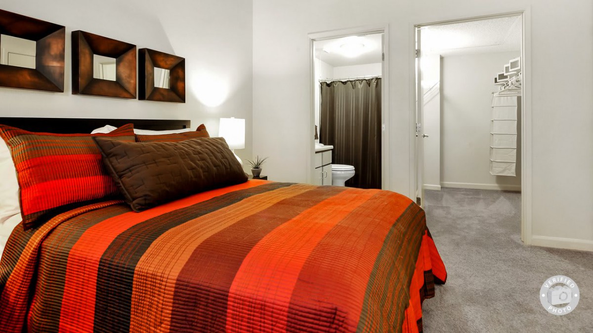 A modern bedroom with a colorful striped blanket and attached bathroom.