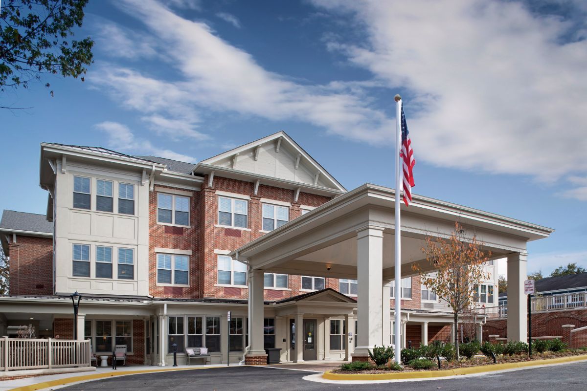 A modern residential building with an American flag outside, under a partly cloudy sky.