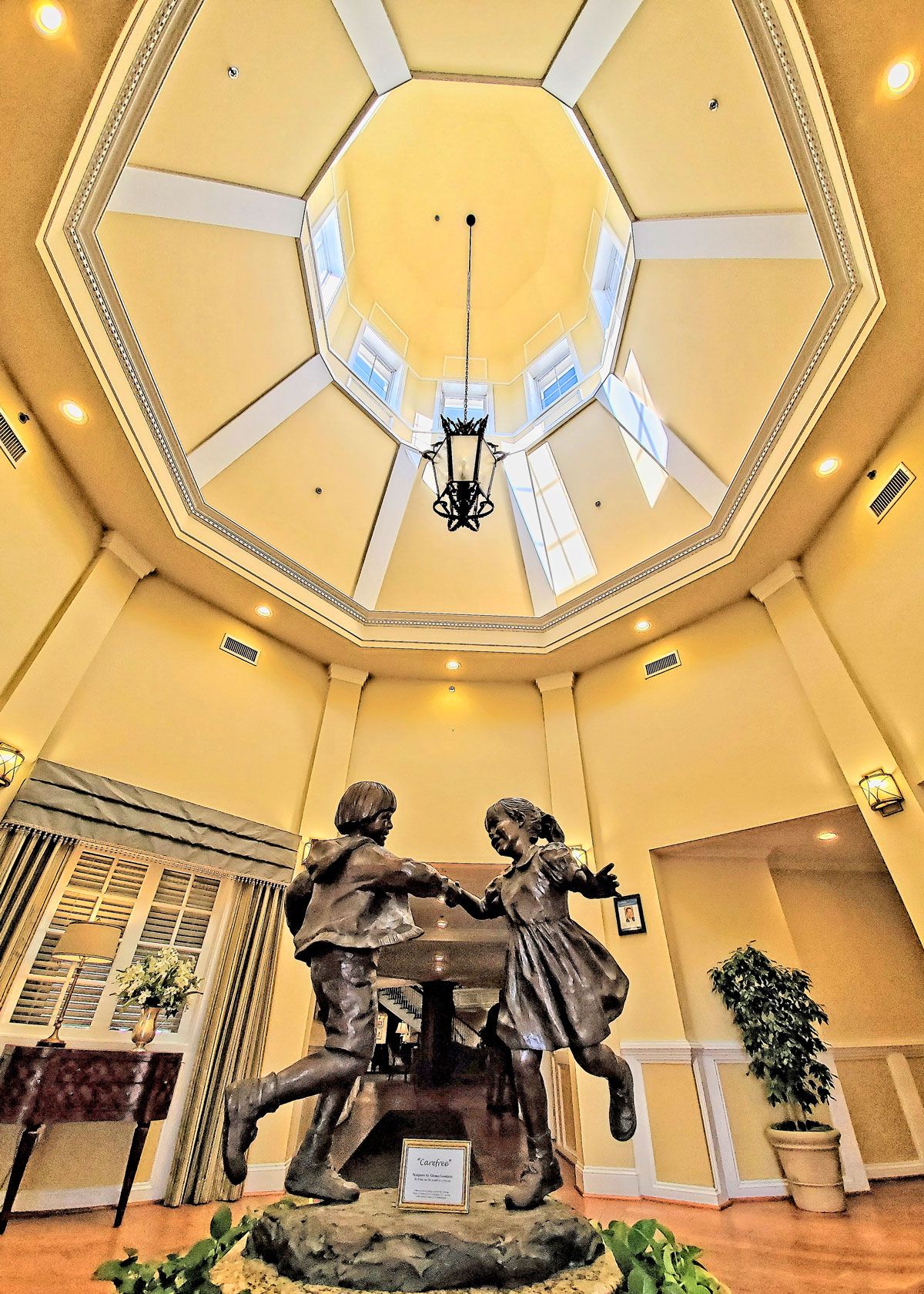 Interior view featuring a sculpture of children dancing under a dome ceiling with elegant lighting.