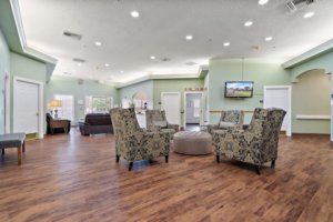 A spacious lobby with patterned chairs, a television, and wood flooring.