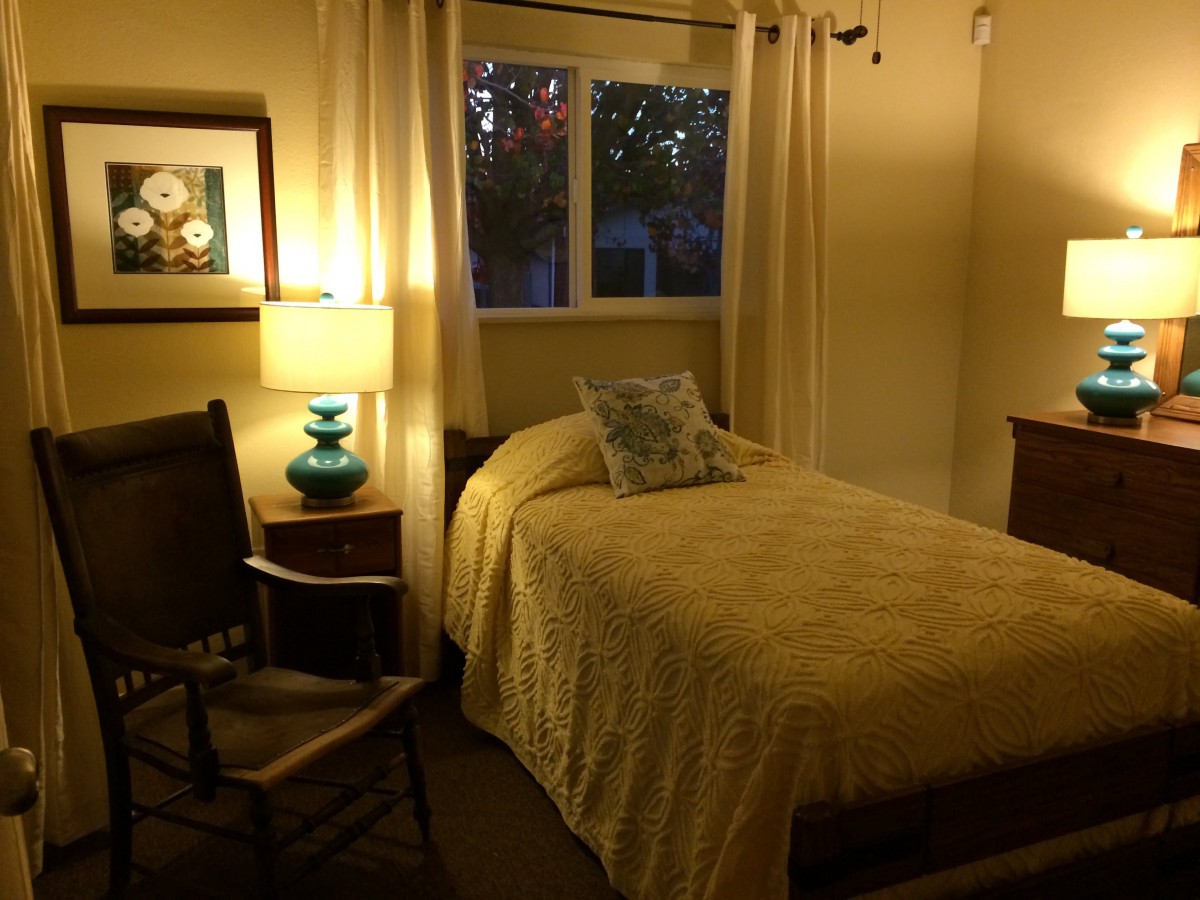 A cozy bedroom with a single bed and glowing lamp.
