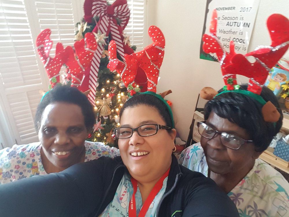 A joyful group celebrating Christmas indoors with reindeer antlers and a decorated tree in the background.
