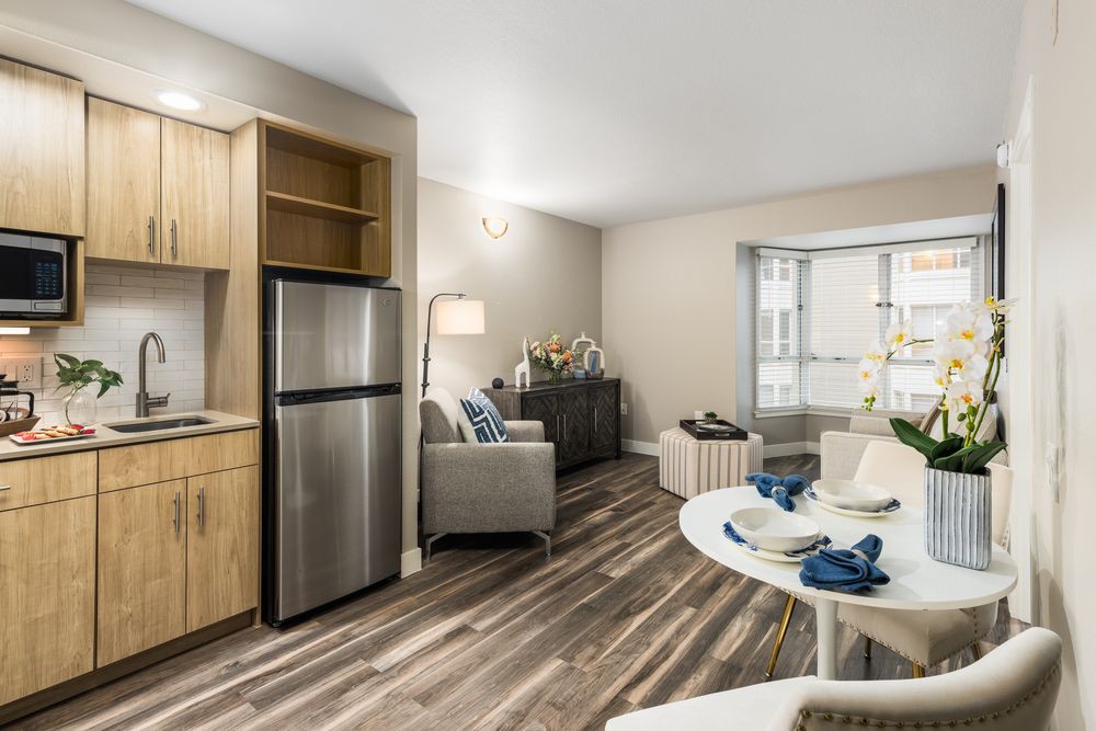A modern open-plan living room and kitchen area with wood flooring and contemporary furnishings.