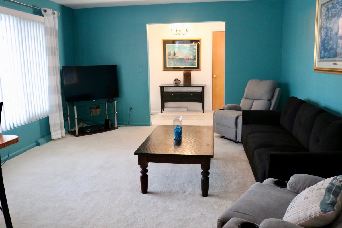 A cozy living room with a sofa, coffee table, and television against a teal accent wall.