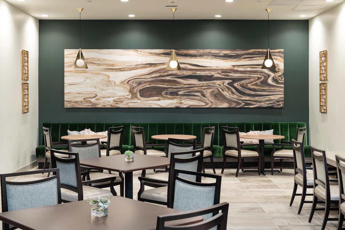 A modern restaurant interior featuring a large abstract artwork and pendant lighting.