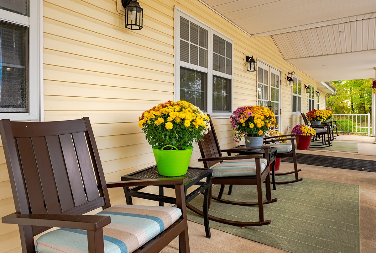 A cozy porch with rocking chairs and colorful flower arrangements.