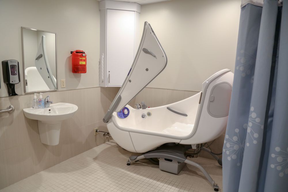A modern, accessible bathtub in a healthcare facility bathroom.