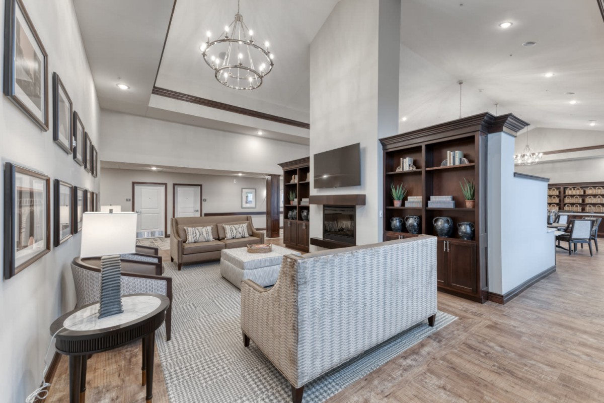 A modern living room with elegant decor, featuring a chandelier, fireplace, and bookshelves.