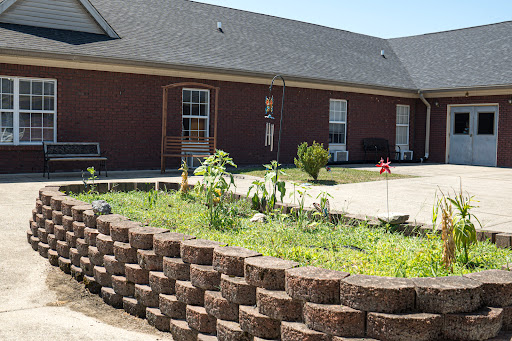 A well-maintained garden area with a brick retaining wall and a residential home in the background.
