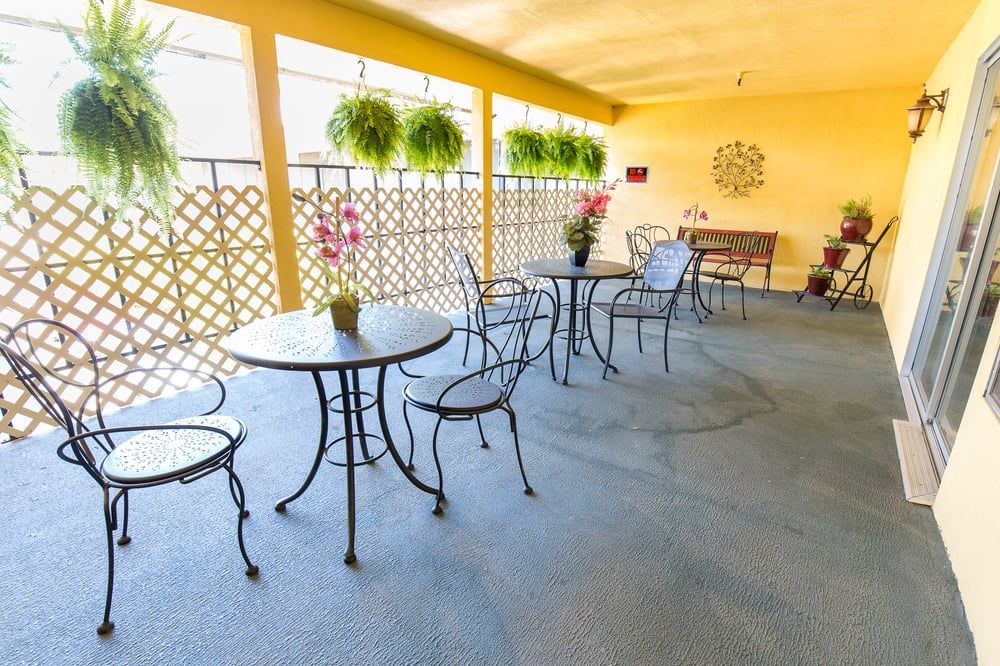 A cozy patio area with metal tables and chairs, adorned with hanging plants and decorative elements.