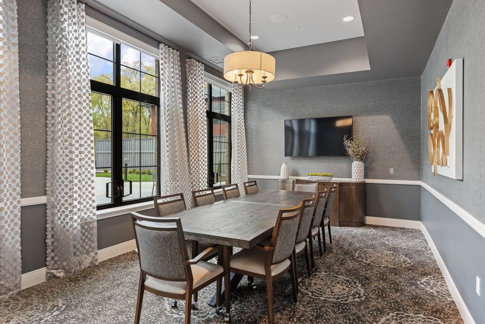 A modern dining room with a long table, elegant chairs, and a stylish chandelier.
