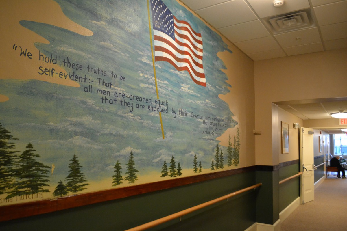 A hallway featuring a mural with the American flag and scenic background.