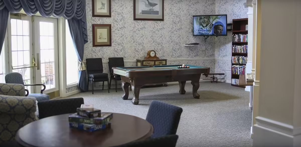 A game room featuring a pool table, chairs, decorative artwork, and a TV on the wall.