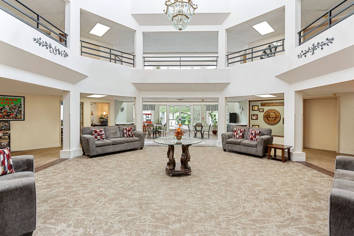 A spacious and elegantly decorated lobby featuring sofas, a central table, and a chandelier.