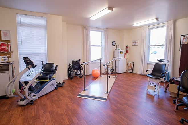 A physical therapy room equipped with exercise machines and parallel bars for rehabilitation purposes.