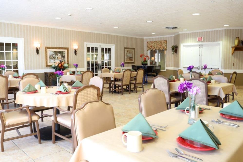 An elegant dining area with neatly arranged tables and chairs, featuring colorful place settings and floral decorations.