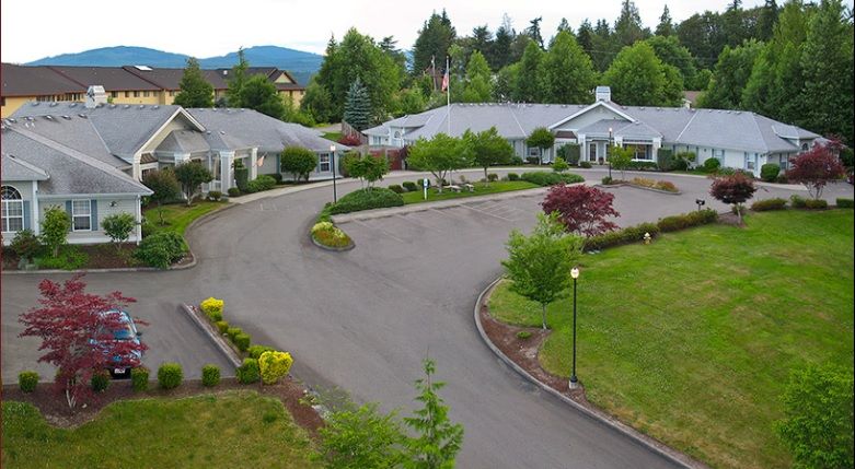 A residential area with buildings surrounded by lush greenery and a winding driveway.