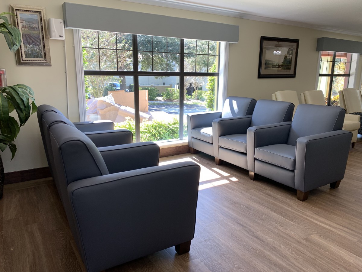 A cozy living room with blue and white sofas arranged around a large window providing ample natural light.