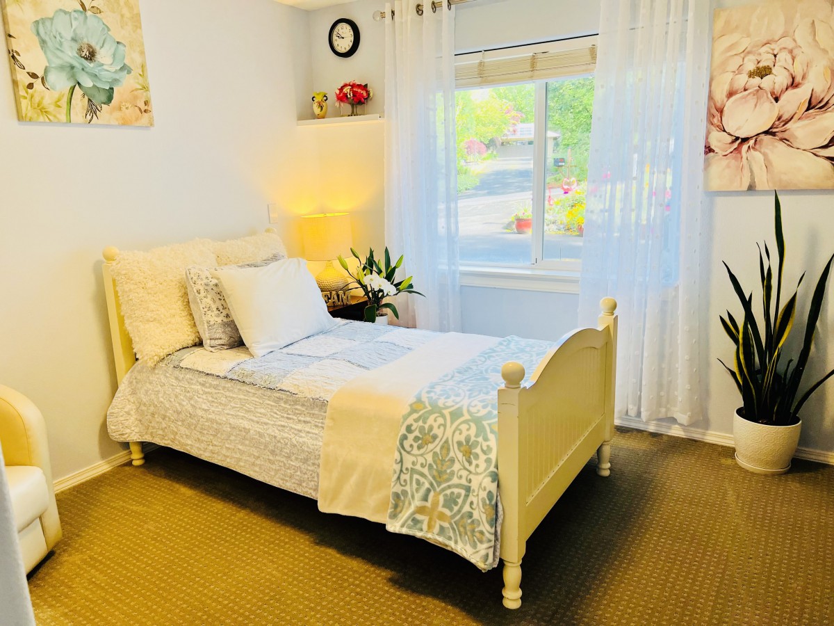 A cozy and bright bedroom featuring a single bed with elegant decor and a window letting in natural light.