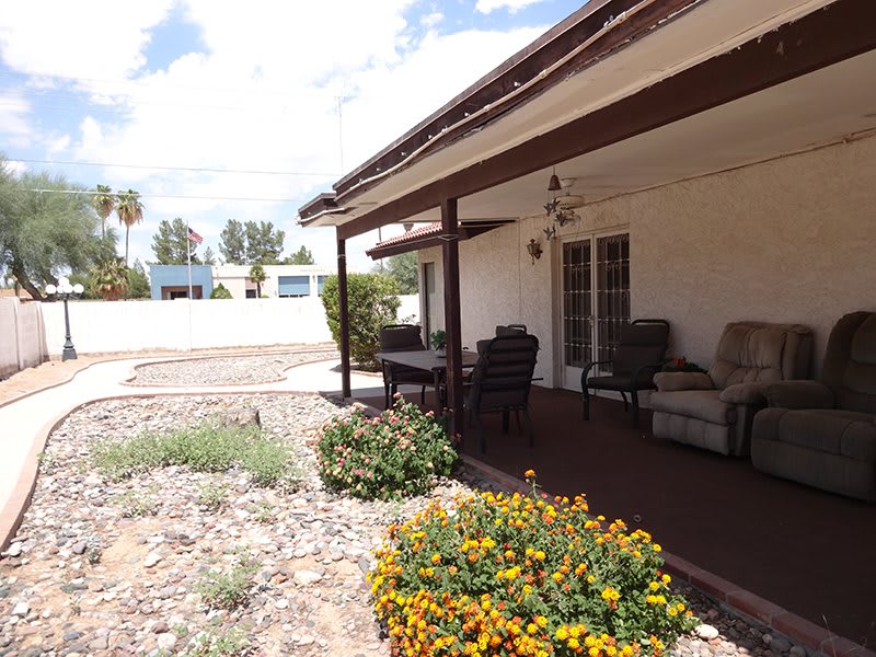 A sunny patio with outdoor seating and vibrant flowers in a desert landscape.