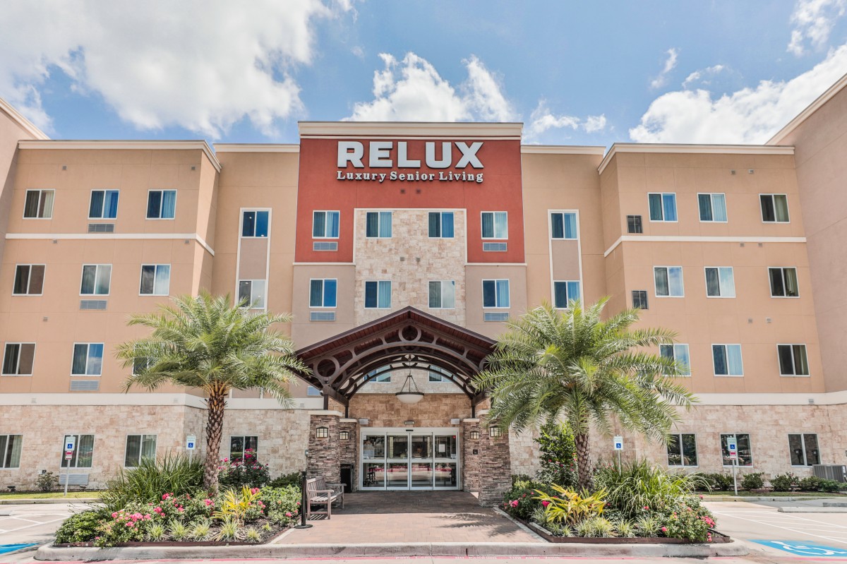 A modern hotel entrance with palm trees and a welcoming design.