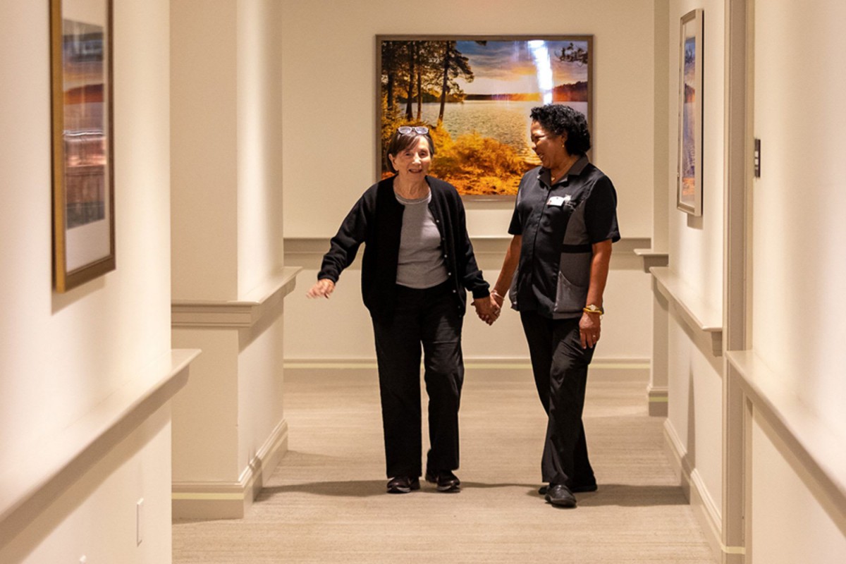 Two people walking hand in hand down a hallway in a healthcare setting.