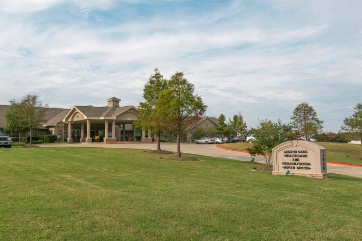 A building with a spacious lawn and a driveway under a blue sky.