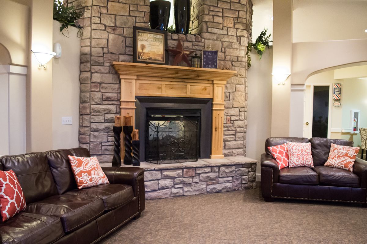 A cozy living room featuring a stone fireplace and comfortable leather sofas.