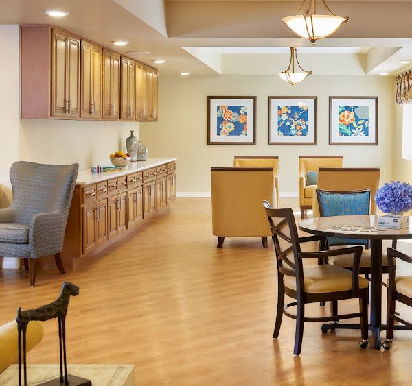 A cozy living room with comfortable seating, artwork on the walls, and warm lighting.