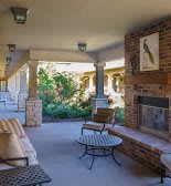A cozy outdoor patio with a fireplace, furniture, and a garden view.