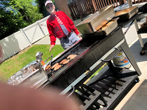 A man grilling burgers on a sunny day.
