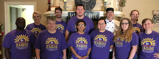 A cheerful team posing together, showcasing their vibrant spirit in matching purple shirts.