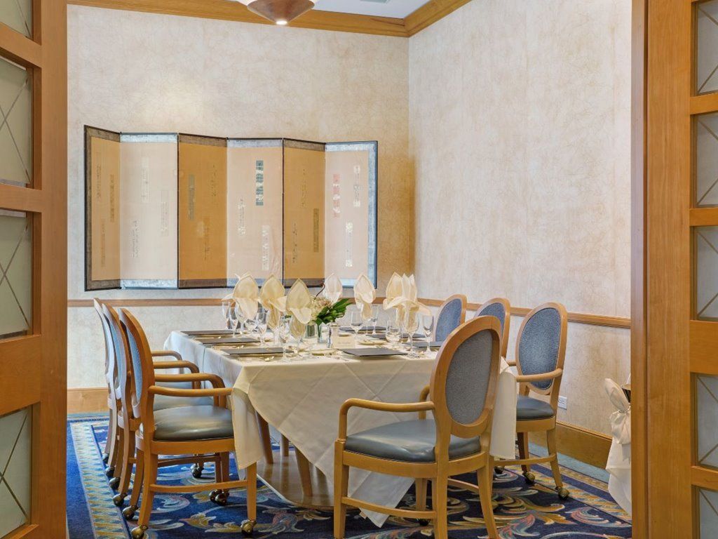 An elegantly set dining table in a formal dining room with chairs and glassware.