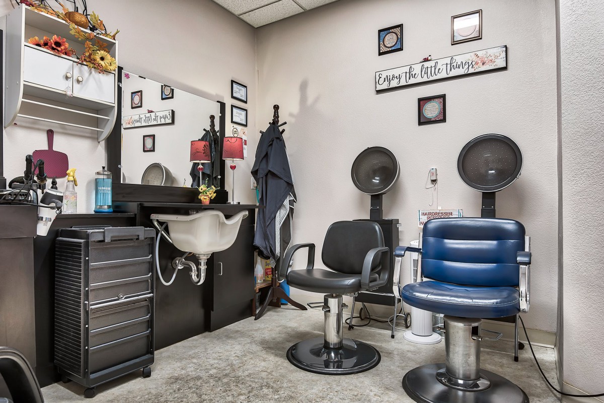 Interior of a hair salon with chairs, a sink, and hair dryers.