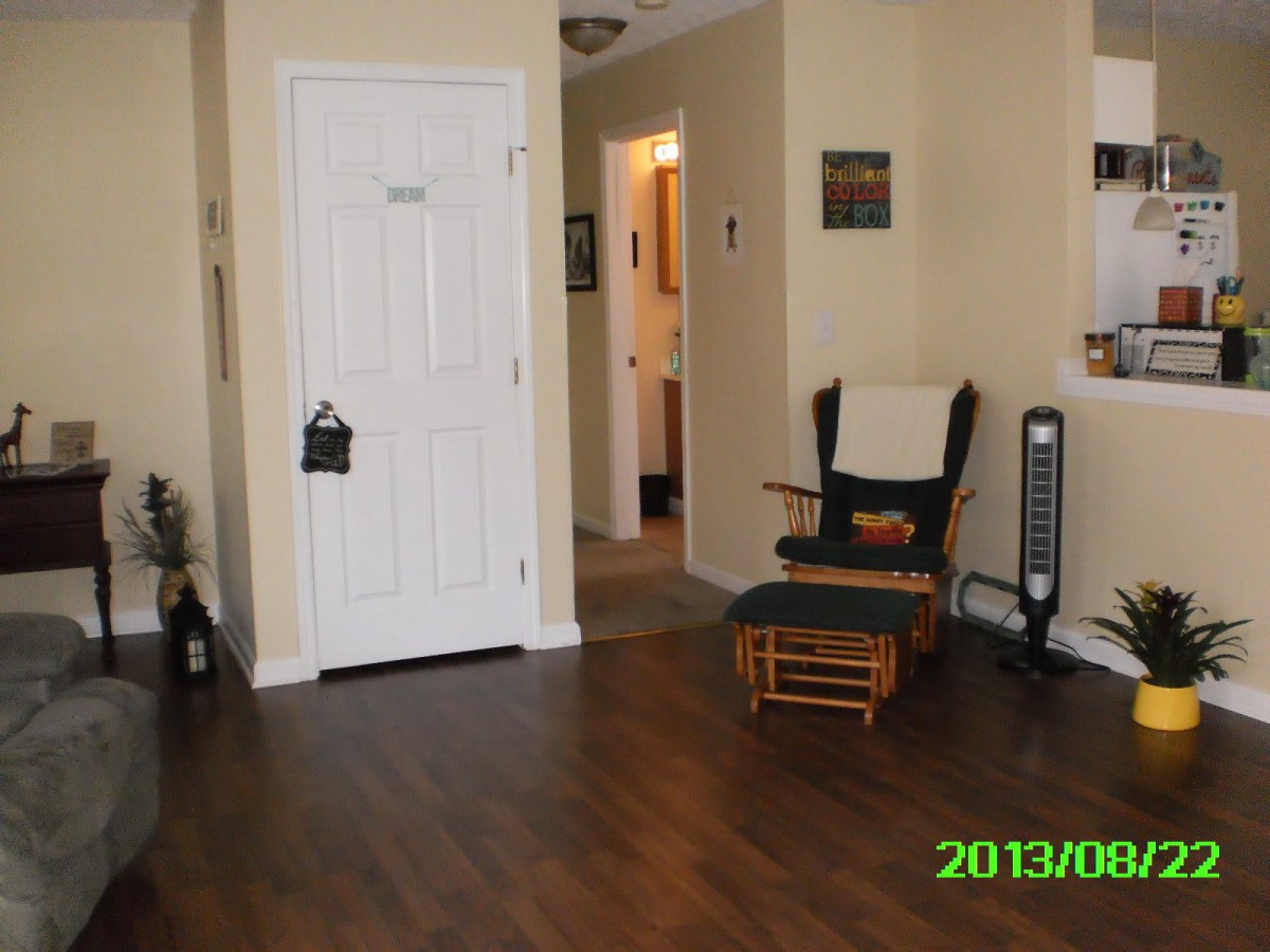 A cozy living room with a rocking chair, fan, and hardwood flooring.