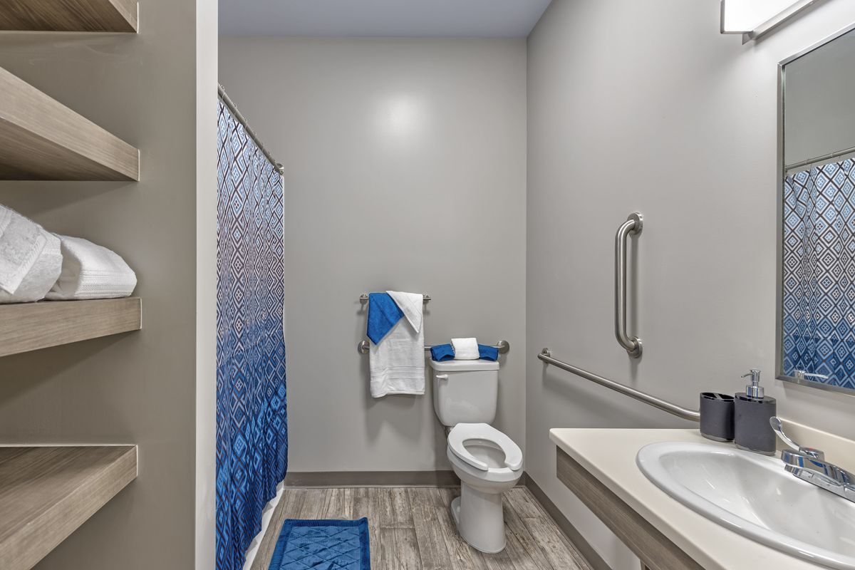 A clean and modern bathroom with blue accents and accessibility features.