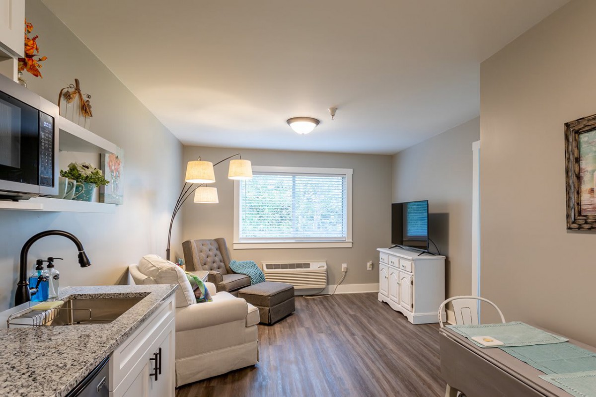 A cozy living room with a sofa, television, and large window providing natural light.