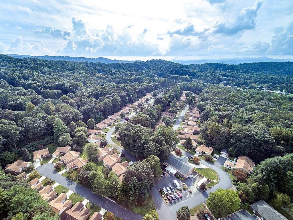 Aerial view of a flooded residential neighborhood surrounded by lush greenery.