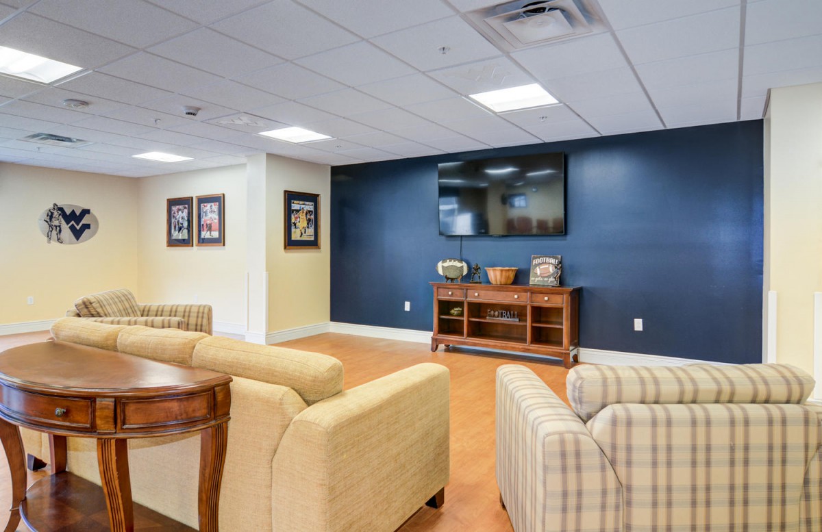 A cozy lounge area featuring comfortable sofas, a large TV mounted on a dark accent wall, and framed artwork.