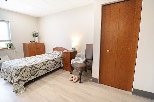 A cozy and minimalist bedroom featuring a single bed, wooden furniture, and warm lighting.