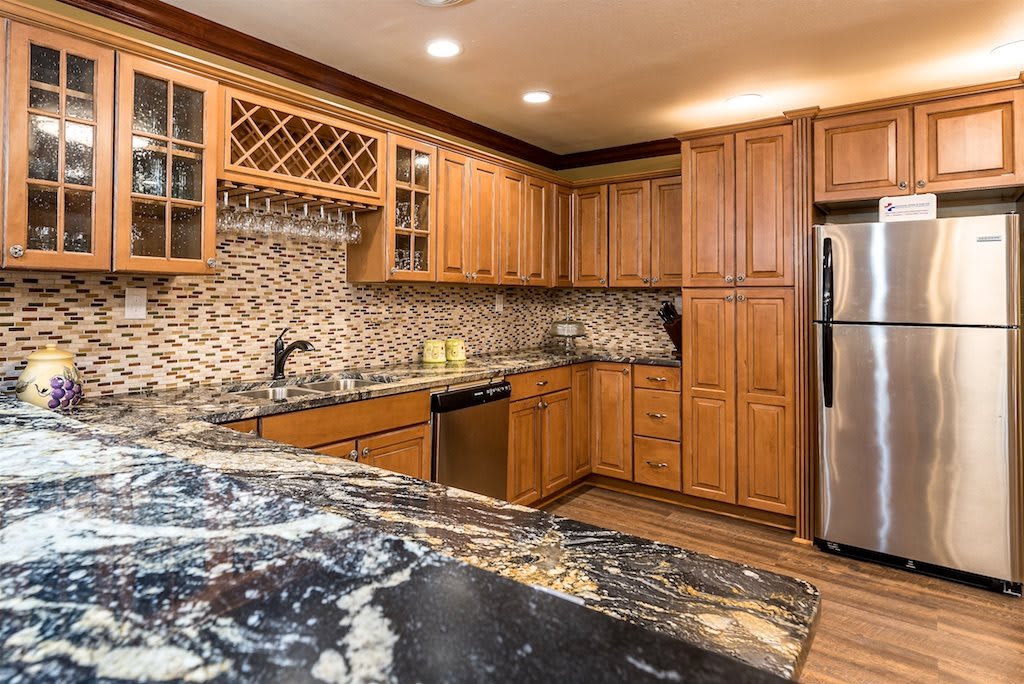 A modern kitchen featuring wooden cabinets, granite countertops, and stainless steel appliances.